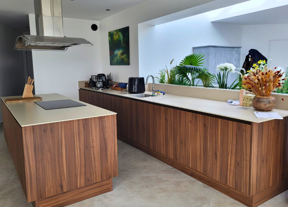 Encimera de cocina Dekton beige con manzana central y mobiliario de madera en proyecto realizado por Mármoles Rustey