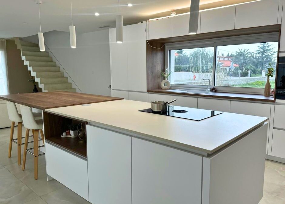 Cocina moderna con manzana central revestida en Dekton Moone blanco cálido mate, superficie ultracompacta resistente a rayaduras y manchas instalada por Mármoles Rustey.