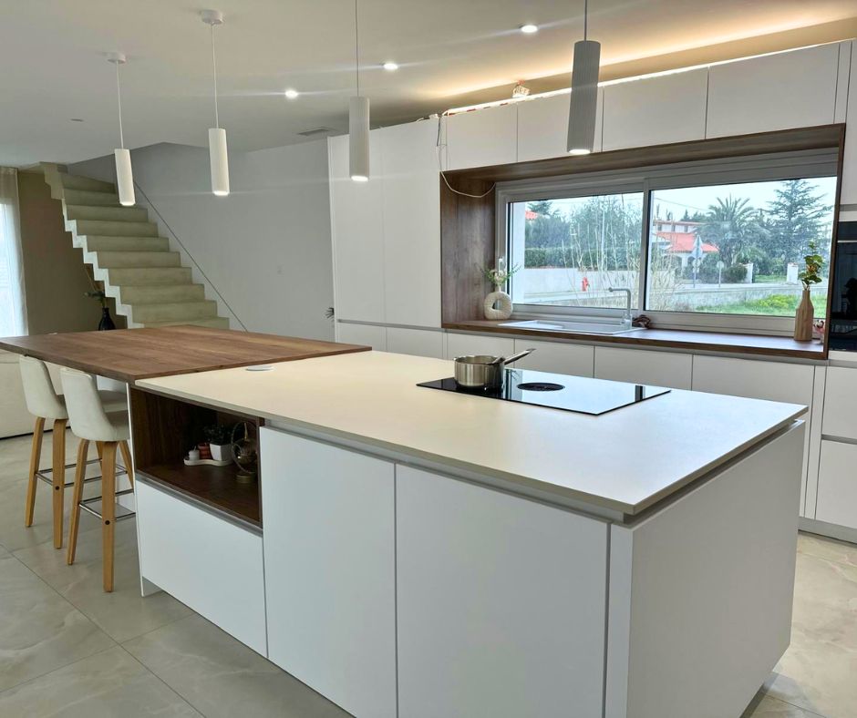 Cocina moderna con manzana central revestida en Dekton Moone blanco cálido mate, superficie ultracompacta resistente a rayaduras y manchas instalada por Mármoles Rustey.